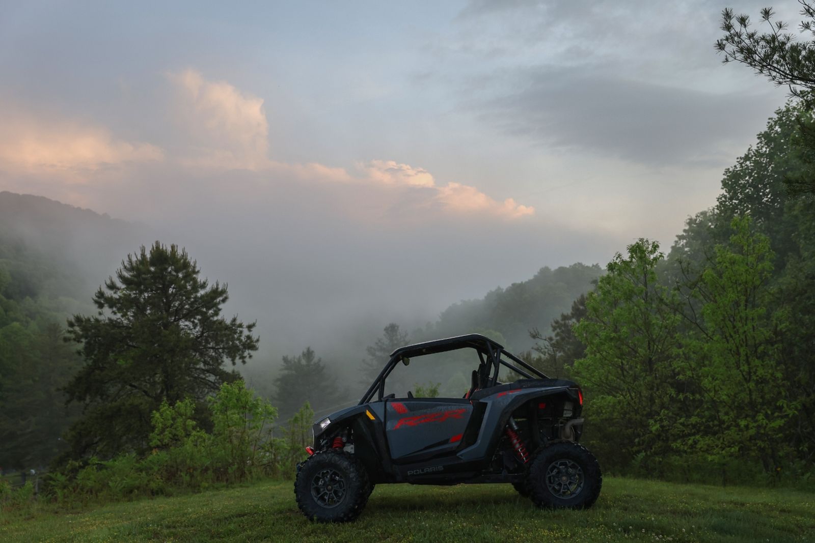 Polaris RZR on a mountain ridge at sunrise above the fog