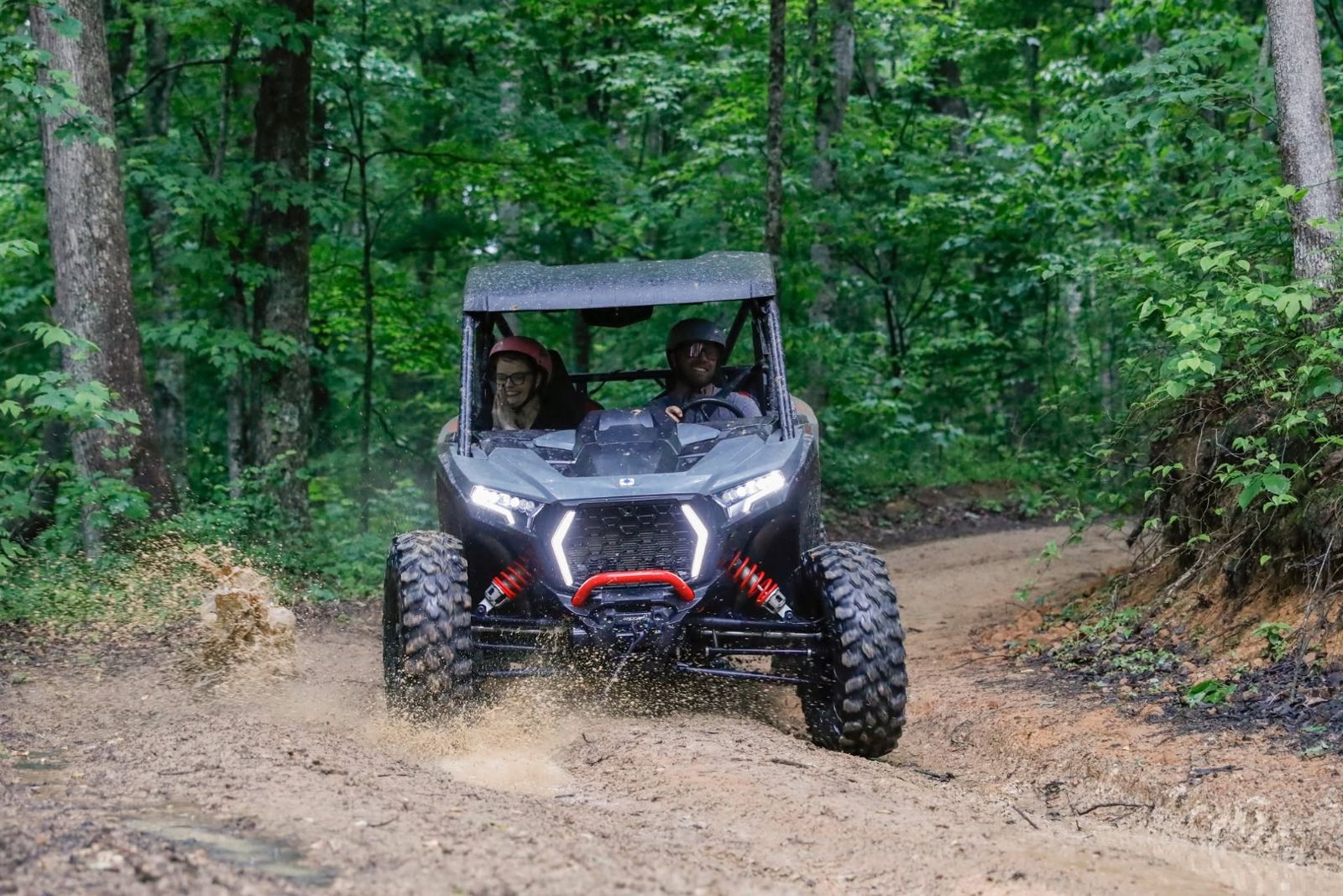 Polaris RZR climbing a dirt trail through the woods